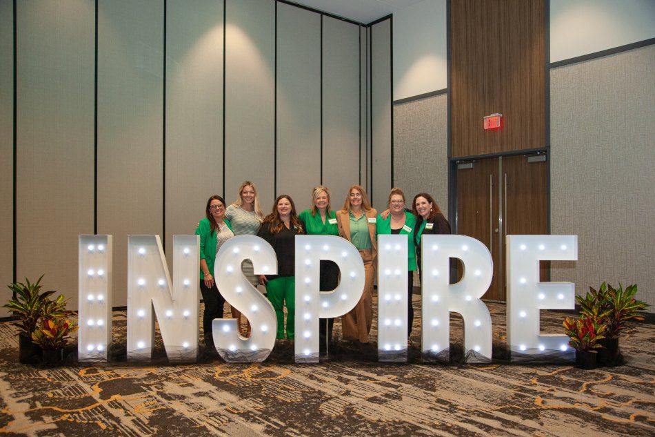 Large Inspire Sign With people posing behind it